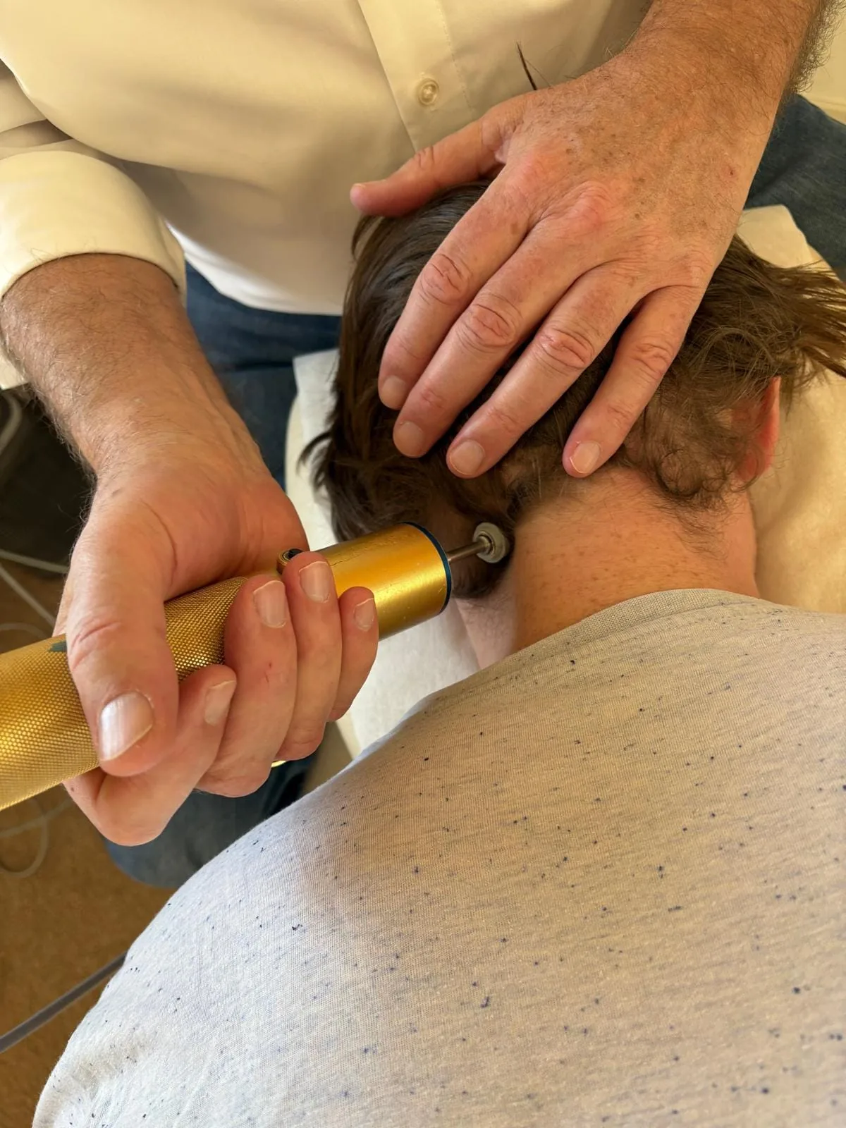 Atlas correction device positioned at the base of the skull on a client lying face down